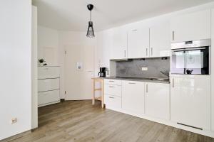 eine weiße Küche mit weißen Schränken und Holzböden in der Unterkunft Ferienwohnung Hafeneck Moba-Travel in Lübeck