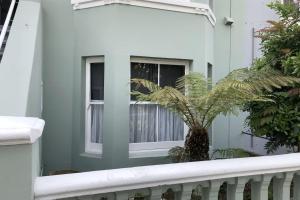 a green house with a palm tree in a window at Broadstairs Terrace: Central Broadstairs Flat in Broadstairs