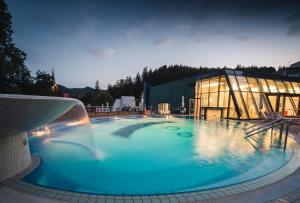 une grande piscine avec une fontaine en face d'un bâtiment dans l'établissement Hotel Švicarija - Terme Dobrna, à Dobrna