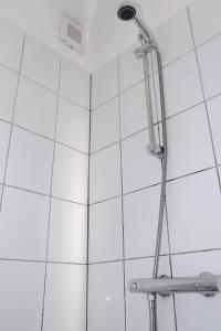 a shower in a bathroom with white tiles at Studio Eelhouse in Amsterdam