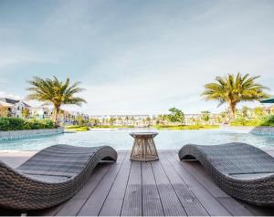 two wicker chairs and a table next to a pool at Novaworld Villas in Phan Thiet