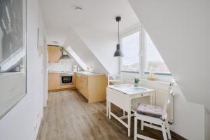 a white kitchen with a table and a window at Ferienwohnung Fährblick Moba-Travel in Travemünde