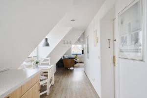 an attic kitchen with white walls and a staircase at Ferienwohnung Fährblick Moba-Travel in Travemünde