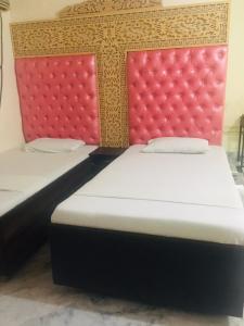 two beds in a room with red and gold headboards at Defence Guest House in Karachi