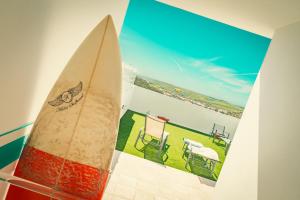 a surfboard on a wall with a picture of a beach at Wayra Lodge [Kanchay] in Raposeira