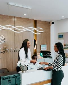 a couple of women standing around a boy at a counter at Rose Garden Private Apartment By LINK in Kigali