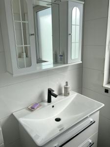 a white bathroom with a sink and a mirror at Casa Hasselholt in Ratzeburg