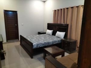a small bedroom with a bed and a couch at Defence Guest House in Karachi