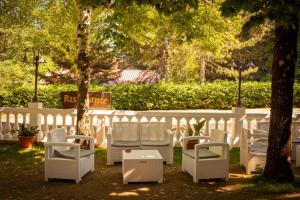 une rangée de chaises blanches dans une cour à côté d'une clôture dans l'établissement Sport Hotel & Residence Il Bivacco del Parco, à Cutura