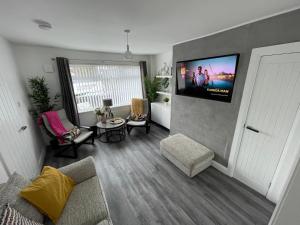 ein Wohnzimmer mit einem Sofa und einem Flachbild-TV in der Unterkunft Casa North Coast in Portrush