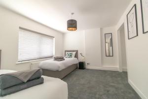 a white bedroom with two beds and a window at Skipton Lodge in Billingham