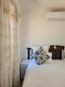 a bedroom with a white bed with a curtain at Heroes Garden Lodge in Pietermaritzburg