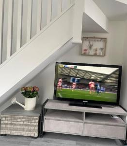 a flat screen tv sitting on a entertainment center under a staircase at The Hideaway-Sharples-Bolton in Bolton