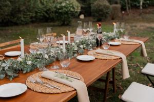 een houten tafel met borden, wijnglazen en kaarsen bij Relais Villa Bianca in Gambassi Terme