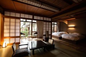um quarto com uma cama, uma mesa e cadeiras em 城崎温泉 旅館 つばき乃 - Kinosaki Onsen Ryokan Tsubakino em Toyooka