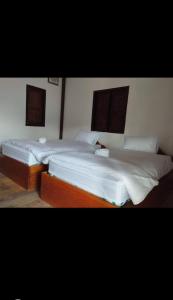 2 camas en una habitación con sábanas blancas en Konglor Khamchalern Guesthouse and Restaurant, en Ban O