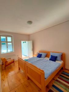 a bedroom with a large wooden bed with blue pillows at Ethno&Coffee House Tulip in Gložan
