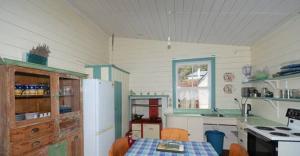 eine Küche mit einem Tisch und einem weißen Kühlschrank in der Unterkunft India House & Ica Whare in Whareama, Nr Riversdale Beach in Whareama