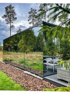 un gazebo in vetro con due sedie su una terrazza di 7Mirrors a Murjāņi