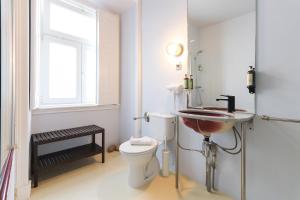 ein Bad mit einem WC, einem Waschbecken und einem Fenster in der Unterkunft Chiado Prime Suites by Homing in Lissabon