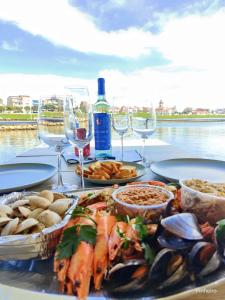una mesa con platos de comida y copas de vino en Floating Experience - Casa flutuante a 25 min do Porto, en Póvoa de Varzim