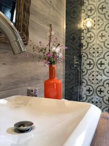 an orange vase with flowers in it on a sink at Botë Farms Agriturismo in Sarandë