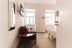 a white room with a chair and a bed at Chiado Prime Suites by Homing in Lisbon
