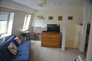 a living room with a blue couch and a tv at The Garrett in Melcombe Regis