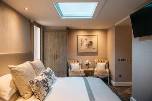 a bedroom with a bed and two chairs and a skylight at The Dean Court in York