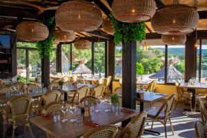 a restaurant with tables and chairs and large windows at Bungalow luxe 3 chambres surplombant le Golf de St Tropez in Gassin