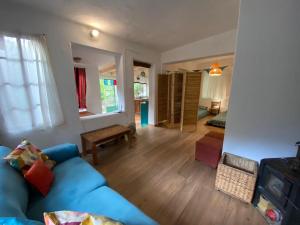 a living room with a blue couch and wooden floors at casasomosamor in San Marcos Sierras