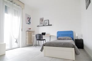 Habitación blanca con cama azul y escritorio. en Tre Re - Luminosa residenza rurale, en Cava Manara