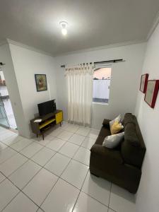 a living room with a couch and a television at Condomínio Serra da Saudade in Piçarras