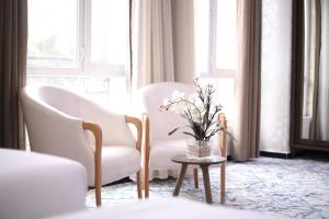 um quarto com duas cadeiras e uma mesa com um vaso de flores em The Castle Hotel em Amã
