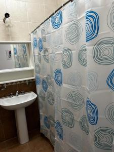 y baño con cortina de ducha y lavamanos. en Apart Hotel Comfort City en Salta