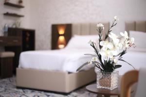 The Castle Hotel في عمّان: إناء من الزهور البيضاء على طاولة في غرفة النوم