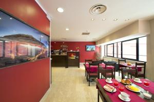 een restaurant met rode muren en tafels en stoelen bij Oasi Village Hotel in Milaan