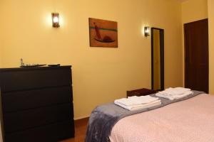 een slaapkamer met een bed en een dressoir met handdoeken erop bij TMP Apartamento in Quarteira
