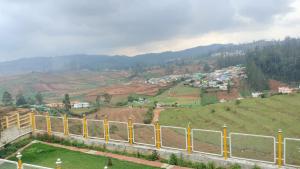 a view of a town on a hill with a fence at Glen Premium Villa By LexStays in Ooty