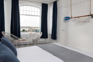 a bedroom with a bed and chairs and a window at Swn y Mor Deganwy in Deganwy
