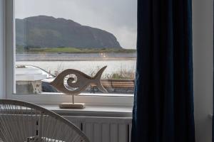a window with a view of the ocean and a boat at Swn y Mor Deganwy in Deganwy