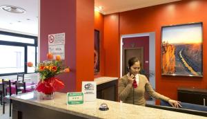 een vrouw staat aan een balie in een kamer bij Oasi Village Hotel in Milaan