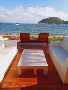 a deck with two couches and a coffee table and the ocean at Beach House à Terre de Haut in Terre-de-Haut