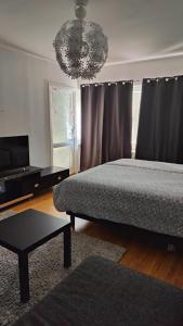 1 dormitorio con cama, mesa y lámpara de araña en Very Nice Apartment 15 minutes from Stockholm, en Trångsund