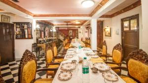 a long dining room with tables and chairs at WelcomHeritage Grace Hotel in Dharamshala
