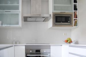 een keuken met witte kasten en een magnetron bij CAROLA l, "apartamento de lujo a 100m playa Catia" in Ribeira