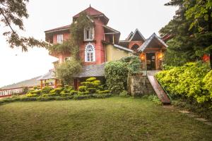 a large house with a large yard in front of it at WelcomHeritage Grace Hotel in Dharamshala