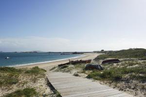 a beach with a wooden path and the ocean at CAROLA l, "Encantador apartamento de estilo marinero a 100m playa Catia" in Ribeira