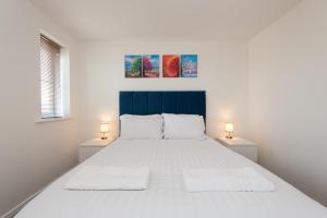 een witte slaapkamer met een groot bed met 2 lampen bij Thinford View in Spennymoor