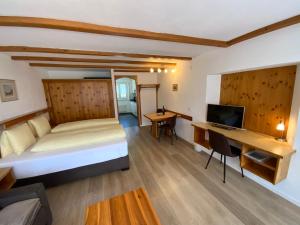 a bedroom with a bed and a desk with a computer at Alfa Appartements Superior in Leukerbad
